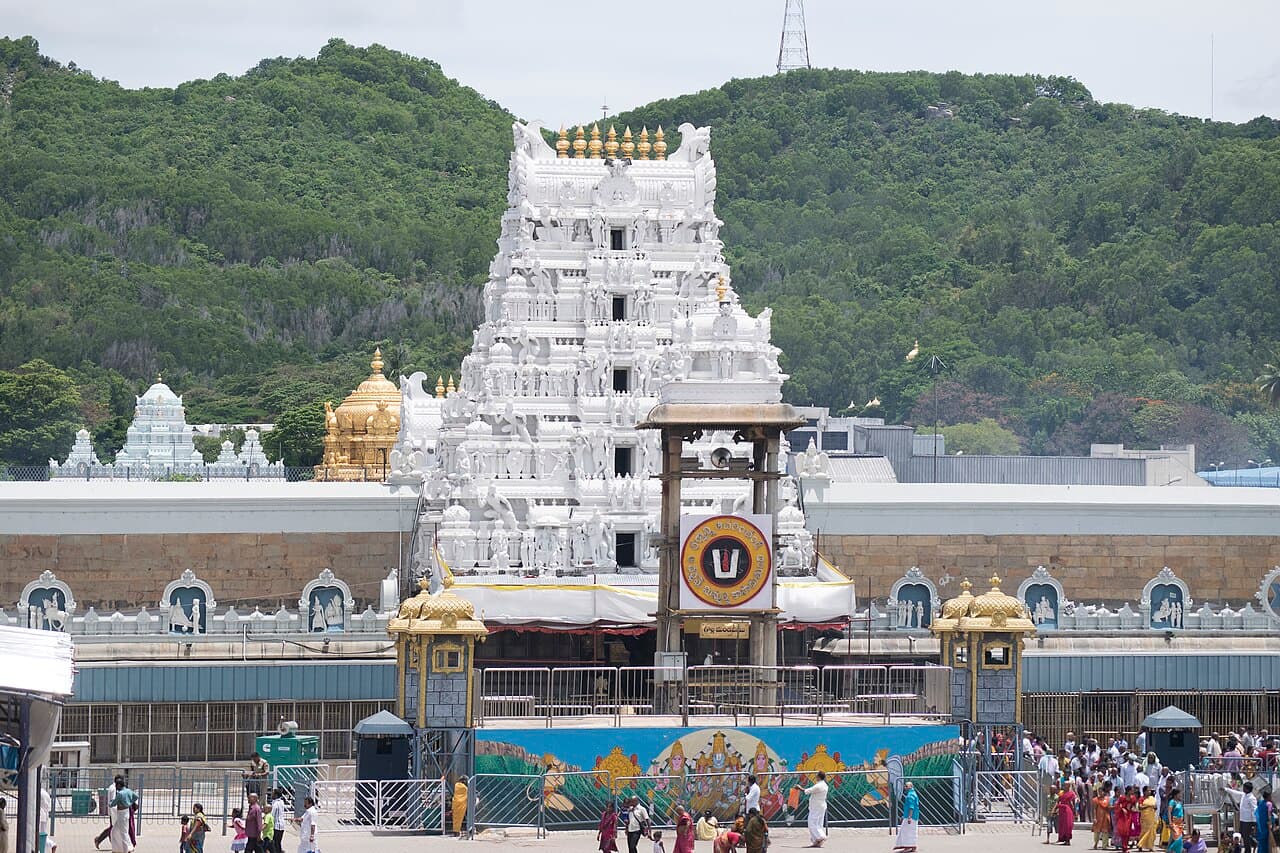The white gopuram of the Sri Venkateswara Temple at Tirumala with forested hills behind