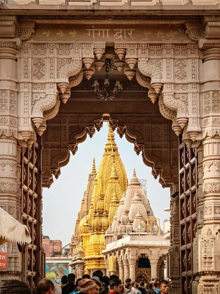 A carved stone gateway framing the golden spire of the Kashi Vishwanath temple